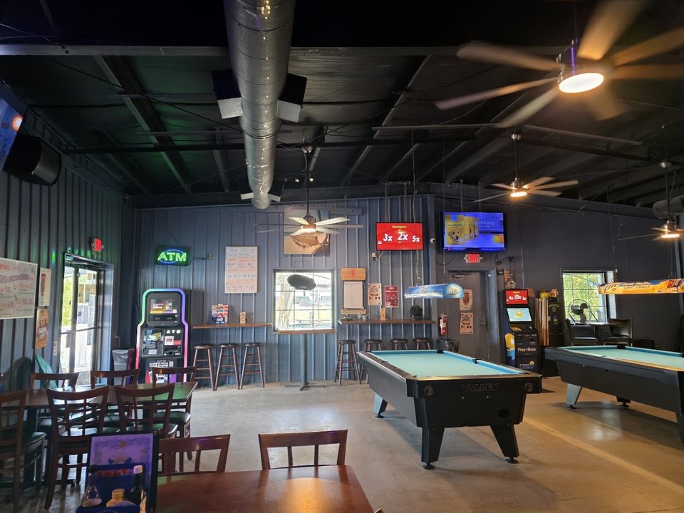 Bright pub interior with bar, stage, and tables.
